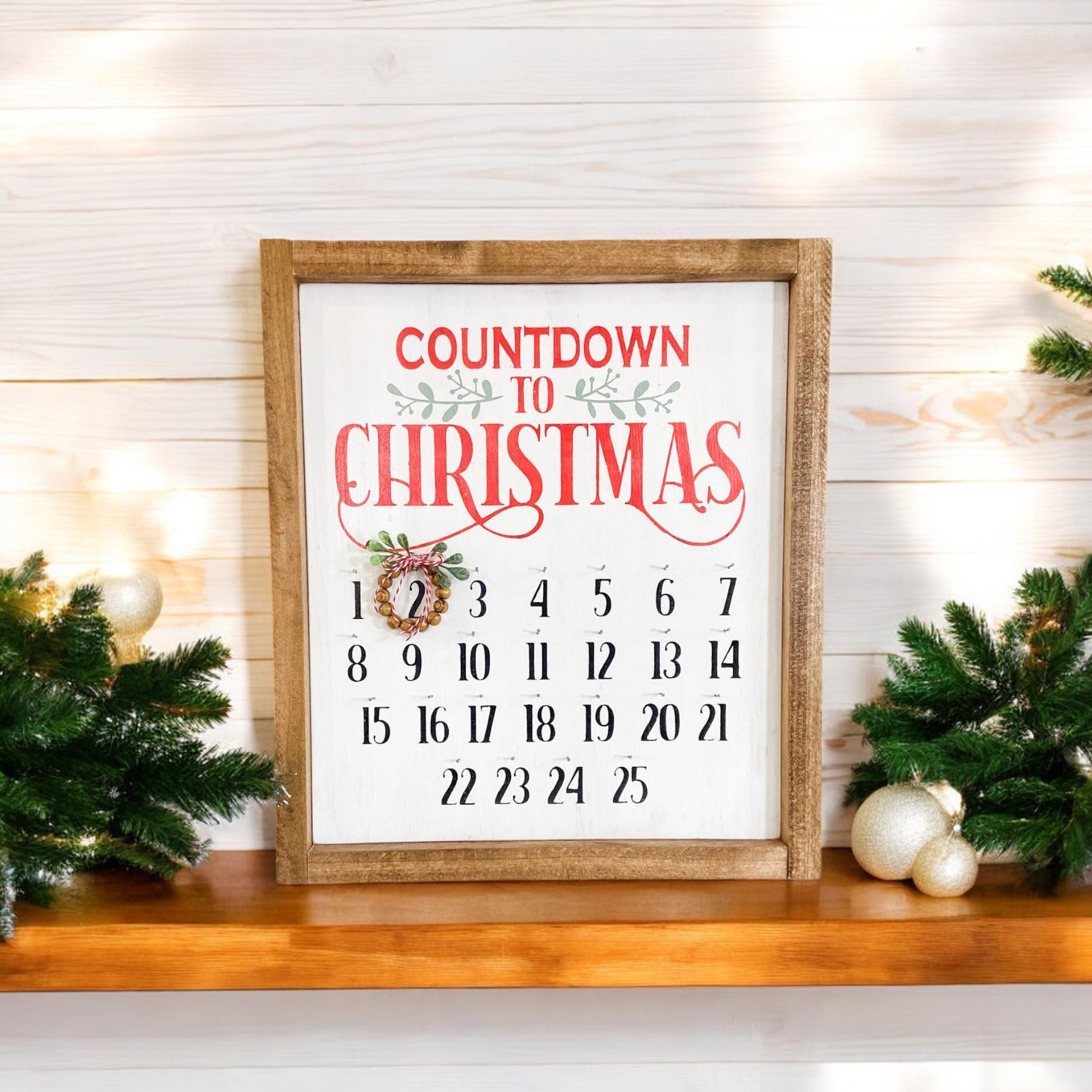 Framed wooden Christmas countdown sign with a movable bead wreath, handpainted white with red, green, and black text, perfect for hanging or displaying on a shelf.