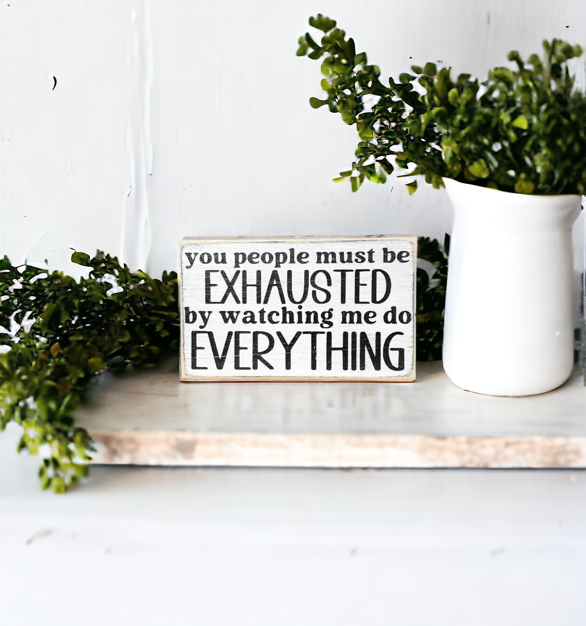 Image: 3.5" x 6" Wooden Desk Sign with black text on white background, saying 'You People Must Be Exhausted By Watching Me Do Everything.' Playful office decor for desks, tables, and shelves.