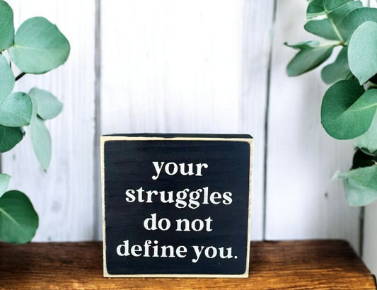 Black handcrafted wooden block sign with white text that reads, "Your struggles do not define you" – inspirational wood sign and uplifting gift.

